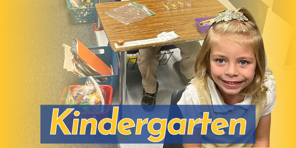 Smiling kindergarten girl in front of a desk